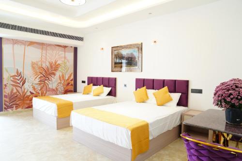 a bedroom with two beds and a painting on the wall at Ascent Eco Resorts & Conventions in Rājānagaram