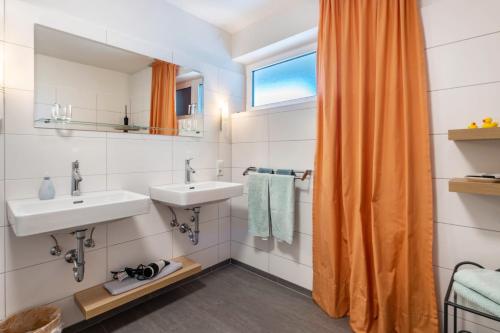 a bathroom with two sinks and an orange shower curtain at Die Ferienwohnung in Bad Bellingen