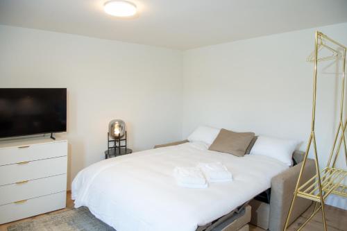 a bedroom with a white bed and a flat screen tv at Stylish Aurora Studio with Mountain Views Lenzerheide in Lenzerheide