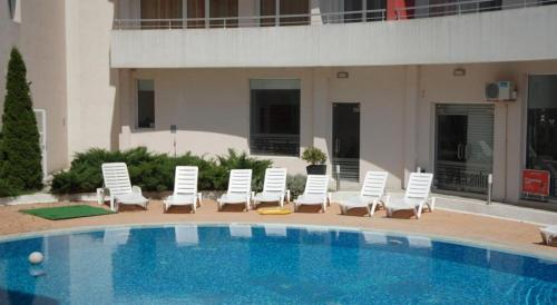 a group of white chairs and a swimming pool at Apartments Victoria in Kranevo