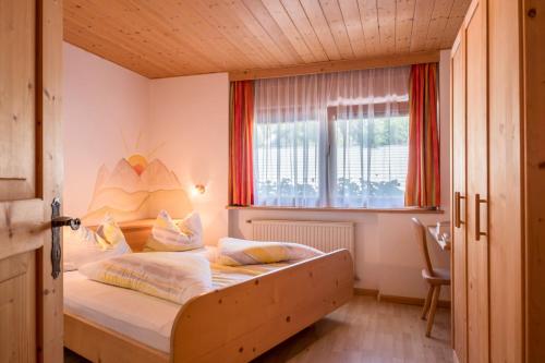 a bedroom with a bed in a room with a window at Gamperhof Apartment Latemar in Collepietra
