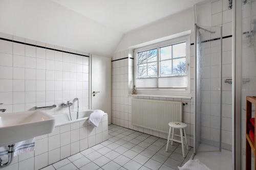 a white bathroom with a tub and a sink at Ferienwohnung Ackerkoog in Niebüll