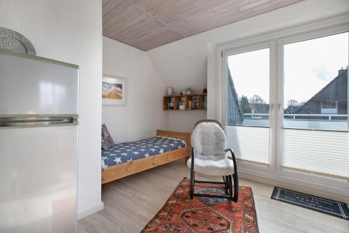 a bedroom with a bed and a chair and a window at Ferienwohnung Ackerkoog in Niebüll