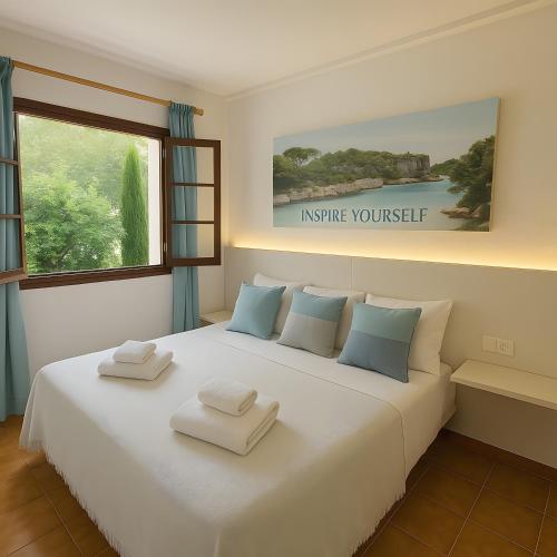 a bedroom with a large white bed with towels on it at Magda - Cala En Porter in Cala en Porter