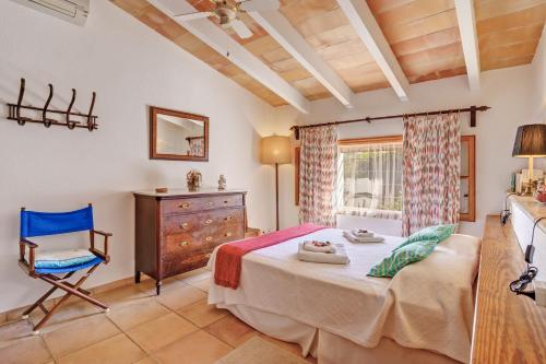 a bedroom with a bed and a chair and a window at Ca les Estamenyes in Pollença