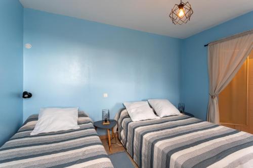 two beds in a room with blue walls at La maison de vacances Mathieu in Artigues