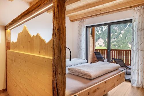 a bed in a room with a large window at Blosegghof Bergchalets Talblick in Racines