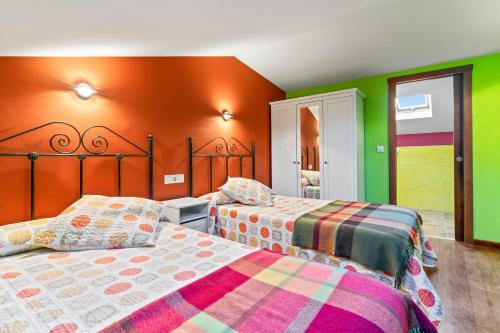 two beds in a room with green and orange walls at Esteiro in Céltigos