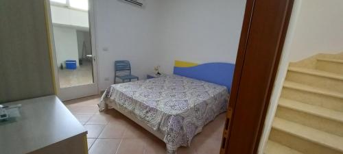 a small bedroom with a bed and a staircase at Villetta Nicola in Salve
