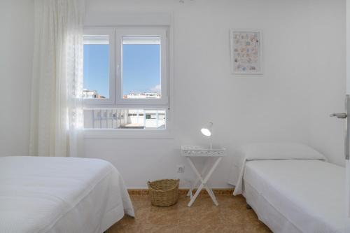 a white bedroom with two beds and a window at Céntrico apartamento en Tarifa in Tarifa