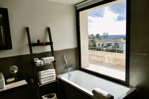 a bathroom with a bath tub with a large window at Ocean Blues in Cala Santanyi
