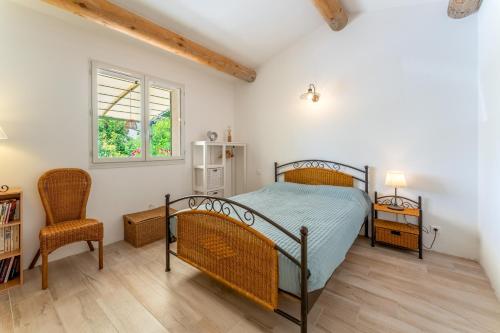 a bedroom with a bed and a chair and a window at Lou Cigaloun in Bédoin