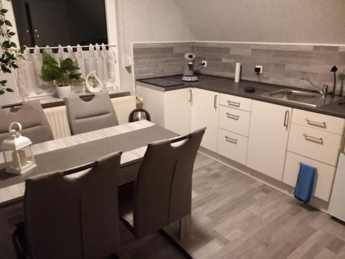 a kitchen with white cabinets and a table and a sink at Ferienwohnung Conrads in Zetel