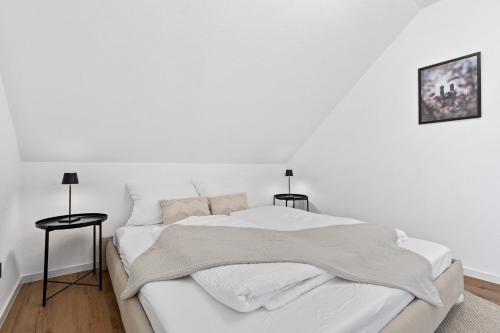 a white bed in a white room with two side tables at Apartment Lio - See und Zentrum in Friedrichshafen
