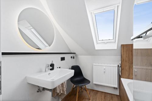 a bathroom with a sink and a mirror and a chair at Apartment Lio - See und Zentrum in Friedrichshafen