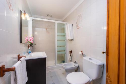a white bathroom with a toilet and a sink at Finca el Cactus in Can Picafort