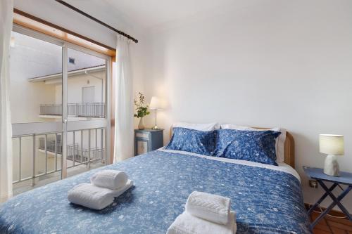 a bedroom with a blue bed with towels on it at Retro Beach House Moledo in Moledo