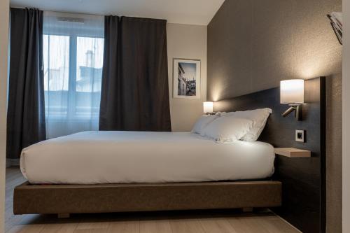 a bedroom with a large bed with a window at Five Resort Cholet Centre in Cholet