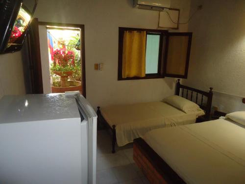 a small room with two beds and a window at Hotel Nueva Granada in Santa Marta