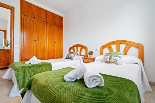 two beds in a room with green sheets and towels at Villa Flor in Les tres Cales