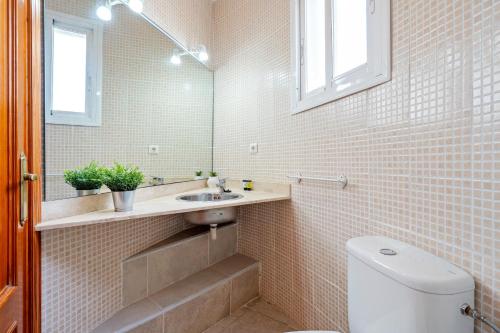 a bathroom with a sink and a toilet and a mirror at Villa Flor in Les tres Cales