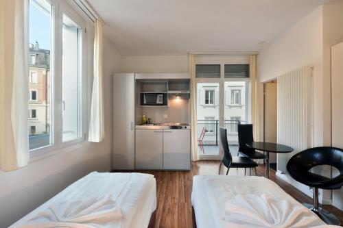 a small room with a bed and a table and chairs at Swiss Star California - Self Check-In in Zürich