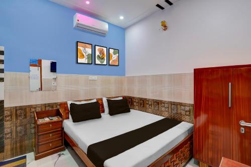 a bedroom with a bed and a blue wall at Super Hotel O Raj Ghat Ayodhya Formerly Shree Siya Raman in Ayodhya