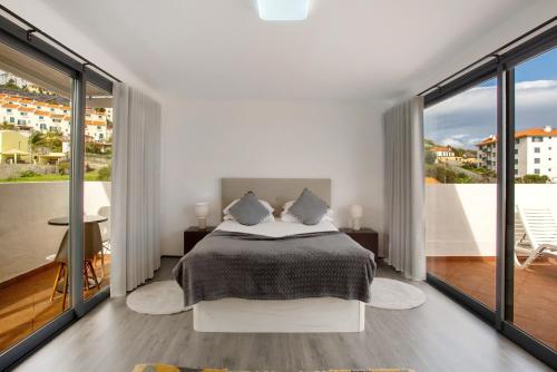 a white bedroom with a bed and a balcony at Apartamento Lolita com Terraço in Caniço