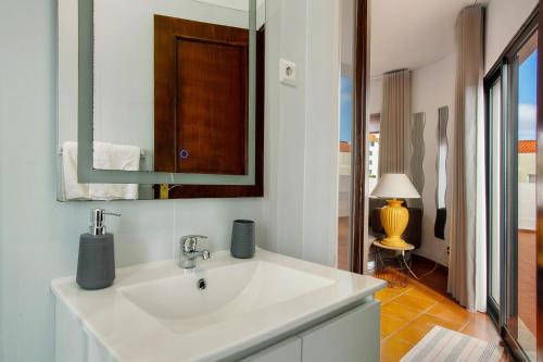 a bathroom with a white sink and a mirror at Apartamento Lolita com Terraço in Caniço