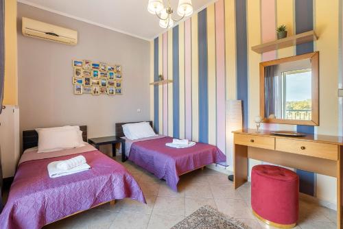 a room with two beds and a desk and a mirror at Rafaela's House 2 in Koskinou