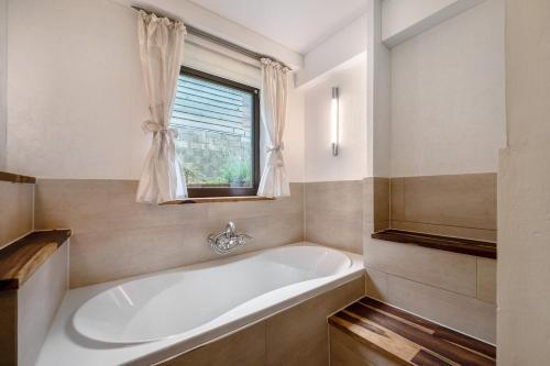 a white bath tub in a bathroom with a window at Ferienwohnung in der Eifel in Pesch