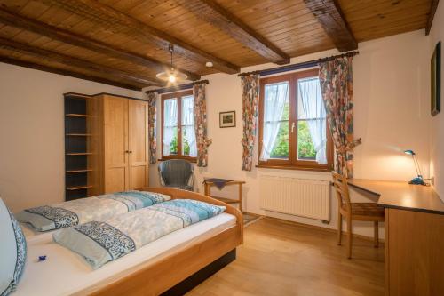 a bedroom with a bed and a desk and windows at Ferienwohnung Risthof 4 in Owingen