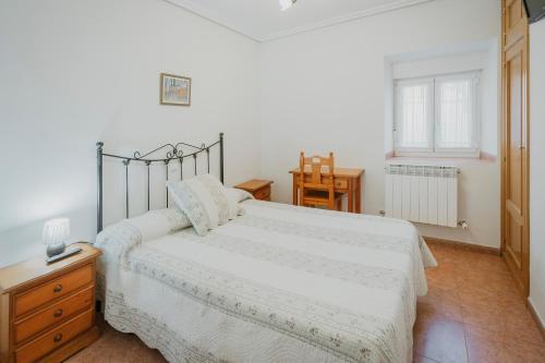 a bedroom with a white bed and a wooden dresser at El Humilladero in Sasamón