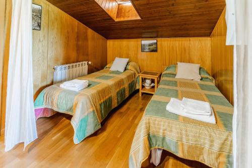 two beds in a room with wooden walls and wooden floors at Valle De Juarros in San Adrián de Juarros