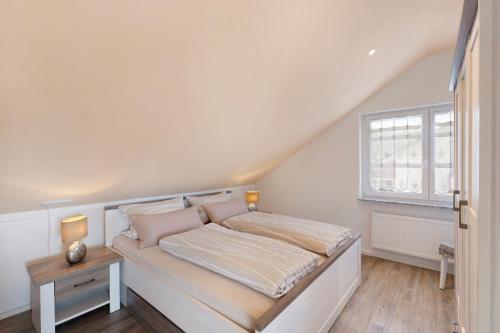 a white bedroom with a bed and a window at Feriendomizil Bergamini in Bischoffingen