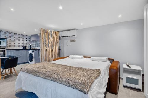 a bedroom with a large bed and a kitchen at Cabanon des Amandiers avec terrasse in Sanary-sur-Mer