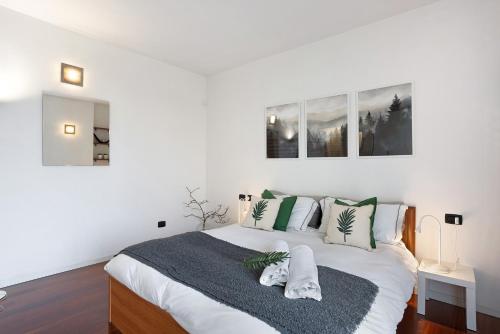 a white bedroom with a large bed with green and white pillows at vb home brianza in Costa Masnaga