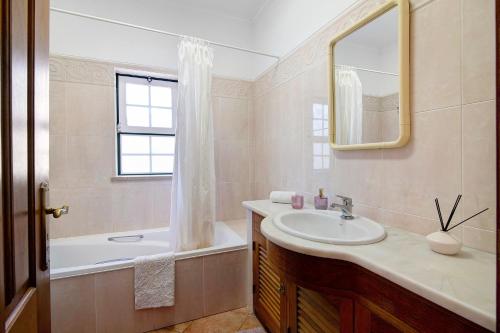 a bathroom with a sink and a tub and a mirror at Casa do Barrocal in Almancil