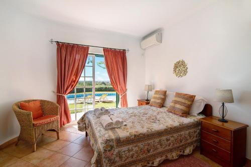 a bedroom with a bed and a window and a chair at Casa do Barrocal in Almancil