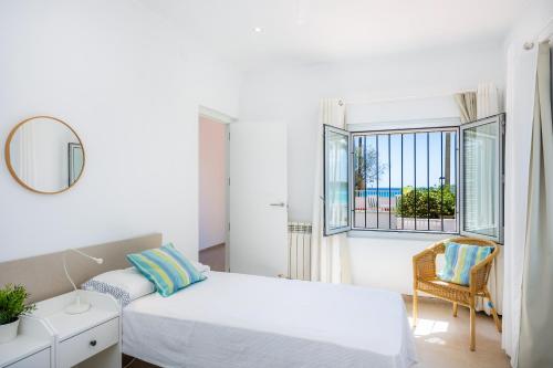 a white bedroom with a bed and a window at Casa Antonia in Cala Millor