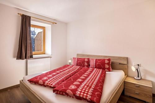 a bedroom with a bed with red and white pillows at Golserhof Kristall in Cadipietra