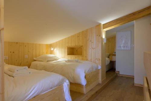a bedroom with two beds in a room with wooden walls at Refuge Mil100 Chalet-spa Luxe 5 in Metzeral