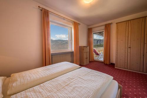 a bedroom with a bed and a large window at Residence Kronstein - Fewo 5 in Tesimo