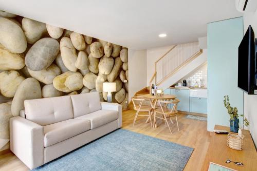 a living room with a white couch in front of a rock wall at Casa do Calhau in Câmara de Lobos