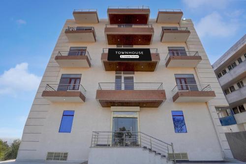 a tall building with balconies and a sign on it at Townhouse Manipal University Highway King Bagru Formerly Golden Hotel in Jaipur