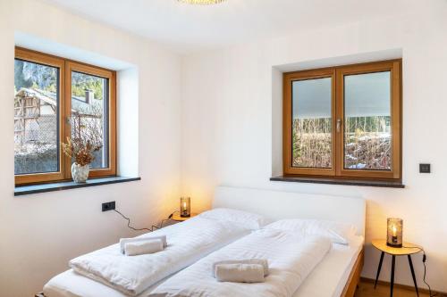 a bedroom with a white bed with two windows at Apartment Luisa in Scharnitz