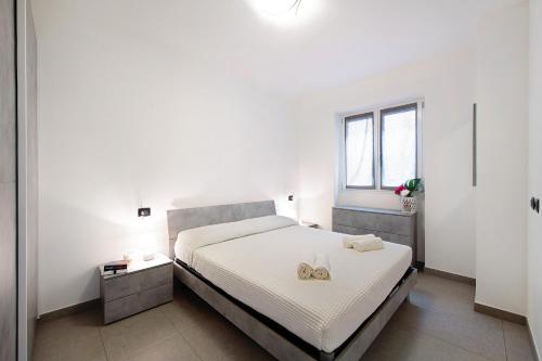 a white bedroom with a bed with two gold wedding rings on it at Appartamento 4 in Nesso