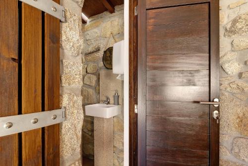 a bathroom with a wooden door and a sink at Casa da Lage in Castelo do Neiva