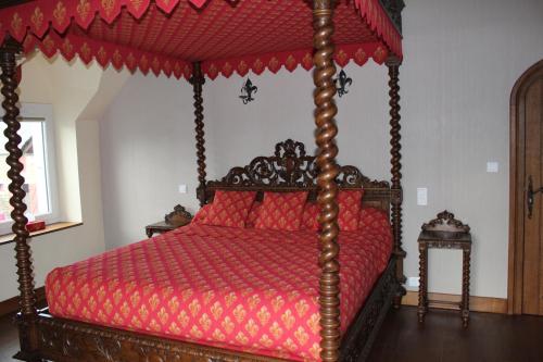 a bedroom with a wooden canopy bed with red sheets at Au p'tit Mont in Ardevon