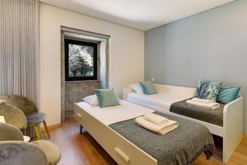 a room with two beds and a chair and a window at Casa da Lage in Castelo do Neiva